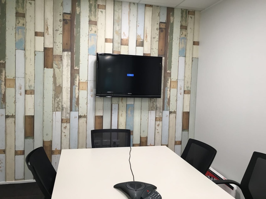 another office tv installation on the wall with funky wallpaper
